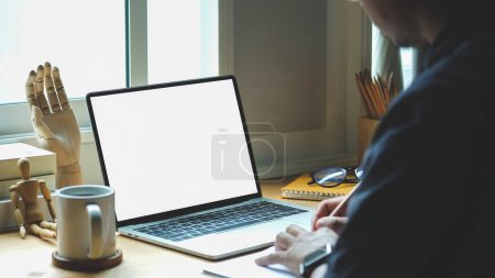 Foto de Side view of businessman using laptop computer while sitting near office window. - Imagen libre de derechos