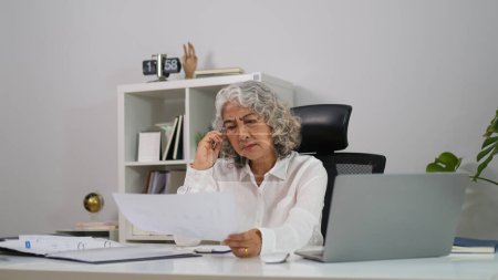 Foto de Stressful middle age business woman sitting in office, having problem with difficult online project. - Imagen libre de derechos