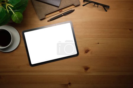 Foto de Vista superior de la tableta digital con pantalla en blanco, taza de café y anteojos en mesa de madera. - Imagen libre de derechos