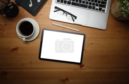 Foto de Asiento plano, vista superior. Tableta digital con pantalla vacía, taza de café y vasos sobre mesa de madera. - Imagen libre de derechos