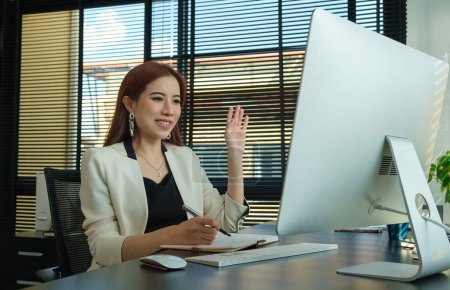 Téléchargez les photos : Millennial businesswoman having conversation with business partner by video call while sitting at her workplace. - en image libre de droit