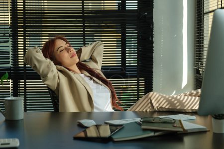 Téléchargez les photos : Femme d'affaires paisible appuyée sur une chaise de bureau confortable avec les yeux fermés - en image libre de droit