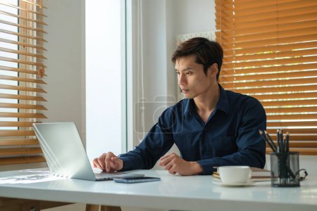 Foto de Empresario empresario masculino enfocado que trabaja en el ordenador portátil en el escritorio de la oficina. - Imagen libre de derechos