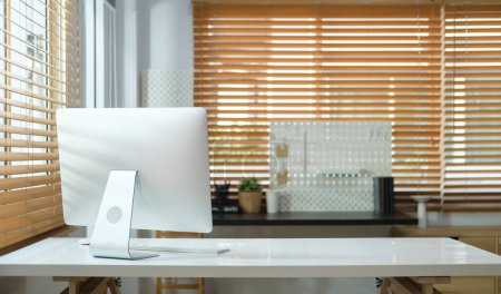 Foto de Interior de la oficina del hogar con monitor de computadora, libros, planta de interior y papelería en la mesa blanca. - Imagen libre de derechos