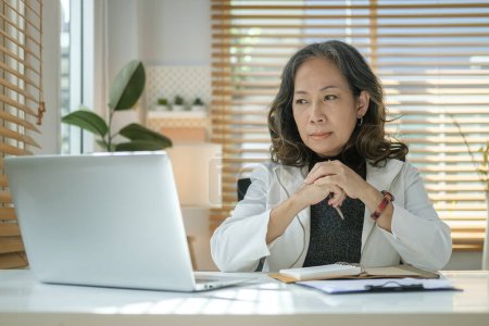 Foto de Enfocado señora de mediana edad de negocios utilizando la computadora viendo webinar en línea en el ordenador portátil en la oficina. - Imagen libre de derechos
