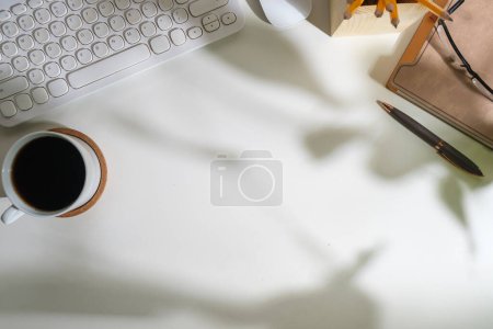 Foto de Escritorio de oficina blanco con diario, teclado, taza de café y vasos. Vista superior con espacio de copia para su texto. - Imagen libre de derechos