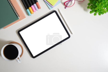 Foto de Tableta digital con pantalla en blanco, vasos, taza de café y papelería sobre mesa blanca. Colocación plana, vista superior con espacio para copiar. - Imagen libre de derechos