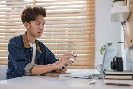 Téléchargez les photos : Adolescent positif faisant des devoirs, regarder tutoriel en ligne sur ordinateur portable. - en image libre de droit