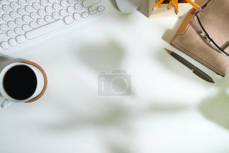 Photo for White working desk with diary, keyboard, coffee cup and glasses. Top view with copy space for your text. - Royalty Free Image