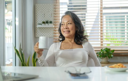 Téléchargez les photos : Femme d'âge moyen paisible buvant son café du matin et regardant par la fenêtre. - en image libre de droit
