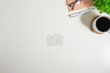 Téléchargez les photos : Vue du dessus du bureau blanc avec tasse à café, lunettes et bloc-notes. Copiez l'espace pour votre texte. - en image libre de droit