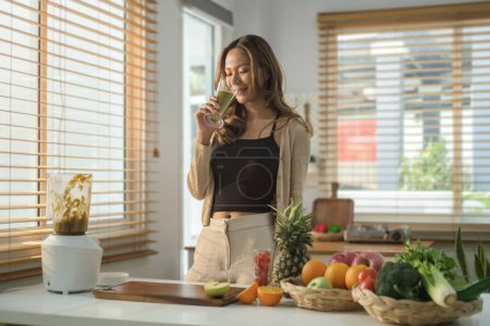 Photo for Beautiful woman drinking healthy green smoothie at home. Healthy eating health, nutrition and vegetarian. - Royalty Free Image