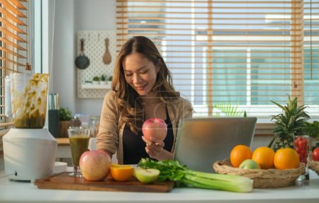 Photo for Beautiful young woman sitting at table with fresh vegetables and fruits, makes her meal plan or healthy recipe on notebook. Healthy lifestyle and dieting. - Royalty Free Image