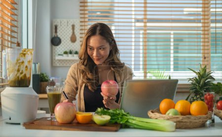 Téléchargez les photos : Jolie jeune femme assise à table avec des légumes et des fruits frais, écrivant des repas hebdomadaires sur un planificateur de repas. Régime alimentaire concept de mode de vie sain. - en image libre de droit