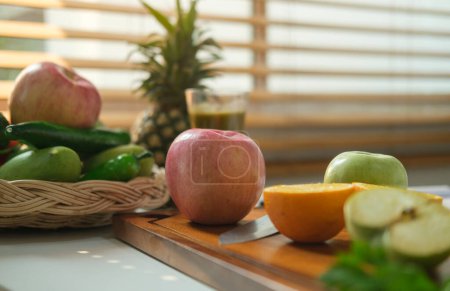 Foto de Alimentación saludable, dieta y concepto de pérdida de peso. Manzana roja fresca y naranja picada en la tabla de cortar . - Imagen libre de derechos