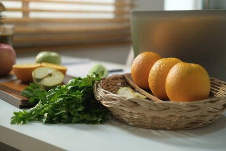 Foto de Dieta, alimentos saludables y un concepto adecuado de nutrición. Frutas frescas, verduras y portátil en la mesa blanca en la cocina. - Imagen libre de derechos