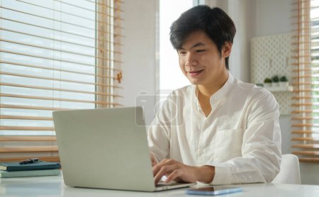 Téléchargez les photos : Beau entrepreneur homme d'affaires regardant l'écran de travail dans Internet, dactylographier e-mail sur ordinateur portable. - en image libre de droit