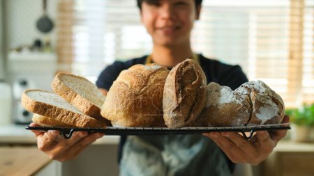 Foto de Tiro recortado de panadero masculino bandeja con pan recién horneado. - Imagen libre de derechos