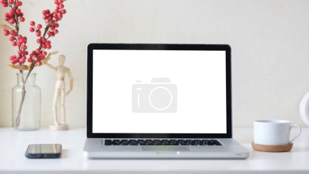 Téléchargez les photos : Vue rapprochée de l'ordinateur portable avec écran vierge, smartphone et tasse à café sur table blanche. - en image libre de droit