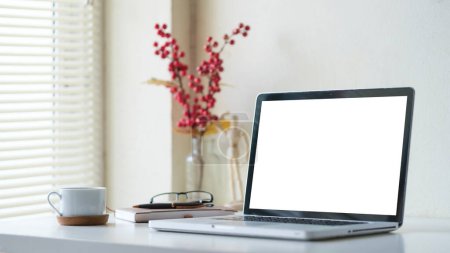 Téléchargez les photos : Intérieur lumineux de bureau à domicile avec ordinateur portable, tasse à café, livres et verres sur table blanche. - en image libre de droit