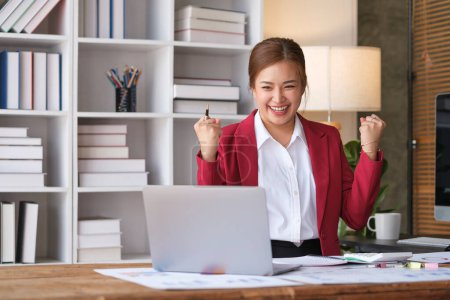 Téléchargez les photos : Femme d'affaires millénaire excitée regardant l'écran d'ordinateur portable et faisant le geste oui, célébrant le succès commercial au bureau. - en image libre de droit