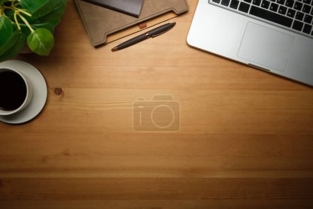 Foto de Ordenador portátil, taza de café, portátil y maceta sobre fondo de madera. Vista superior con espacio de copia. - Imagen libre de derechos