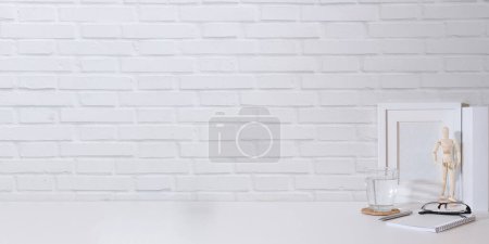 Photo for Minimal workplace with books, glass of water and eyeglasses on white table. Copy space for your text. - Royalty Free Image