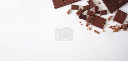 Téléchargez les photos : Morceaux de chocolat noir isolés sur fond blanc. Pose plate, vue du dessus avec espace de copie. - en image libre de droit