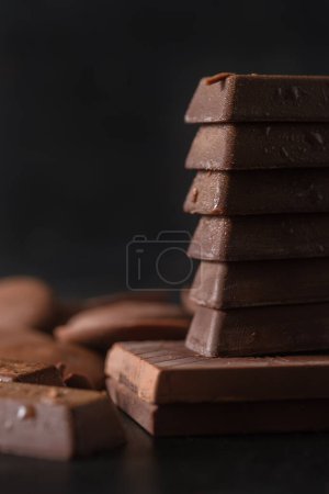 Photo for Stack of milk chocolate on dark background. Dessert food background. - Royalty Free Image
