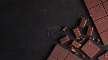 Photo for Top view of bars and pieces of dark chocolate on dark concrete background with copy space. - Royalty Free Image