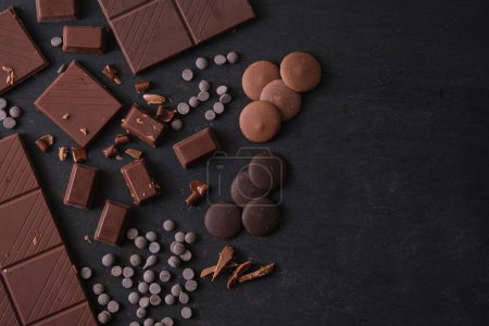 Photo for Top view of bars and pieces of different milk and dark chocolate on dark concrete background with copy space. - Royalty Free Image