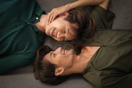Foto de Hermosa pareja gay joven acostada en el sofá, abrazándose juntos. Concepto LGBT, homosexual, de amor e igualdad de género. - Imagen libre de derechos