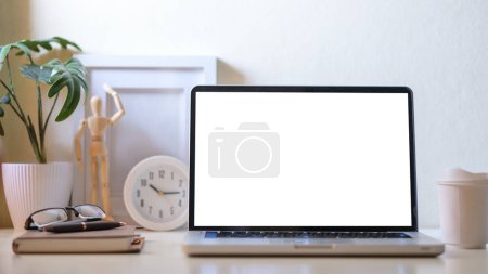 Photo for Modern workplace with laptop computer, coffee cup, potted plant and picture frame. Blank screen for your advertise text. - Royalty Free Image