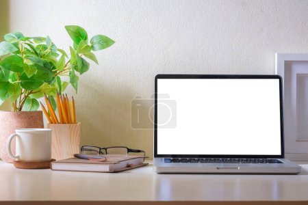 Photo for Home office desk with laptop, coffee cup, potted plant and stationery. Blank screen for your advertise text. - Royalty Free Image