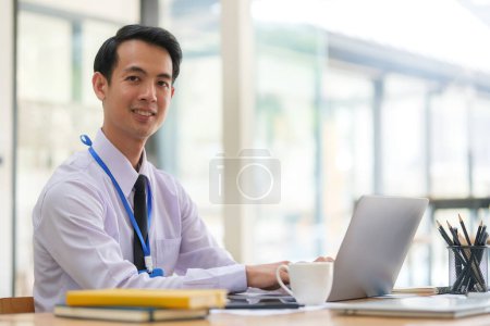 Photo for Portrait of millennial male office worker using laptop on wooden desk. - Royalty Free Image