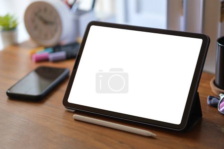 Photo for Closeup view of digital tablet with white blank screen and smartphone on wooden work desk. - Royalty Free Image