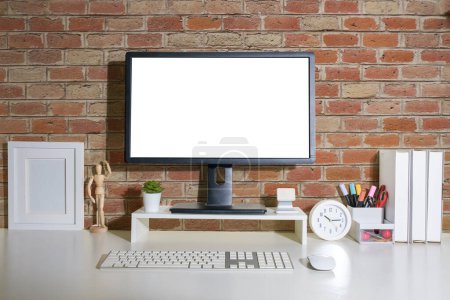 Téléchargez les photos : Vue de face écran d'ordinateur de bureau vierge, cadre photo et porte-crayon sur la table blanche. - en image libre de droit