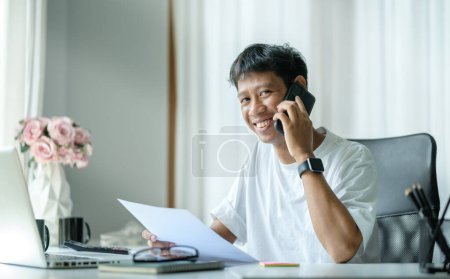 Foto de Smiling asian man advisor sitting at workplace in modern office and talking to client, solve issues remotely. Business conversation concept. - Imagen libre de derechos