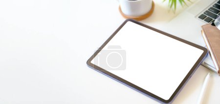 Téléchargez les photos : Tablette numérique avec écran vide sur tasse à café et bloc-notes sur bureau blanc. Copiez l'espace pour votre texte. - en image libre de droit