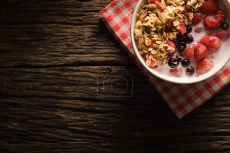 Photo for Healthy breakfast. Crunchy oat granola with fresh milk and berries in a white bowl on wooden background.  Dieting and weight loss concept. - Royalty Free Image