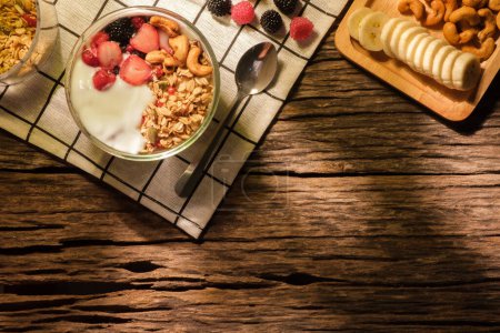 Foto de Yogur con granola y bayas para un desayuno saludable en la mesa de madera. Vista superior con espacio. - Imagen libre de derechos