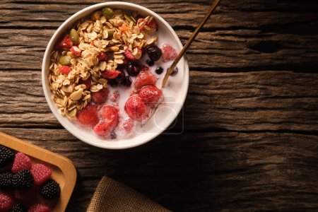 Photo for Crunchy oat granola with fresh milk and berries in bowl on wooden background. Healthy breakfast, vegan, dieting and weight loss concept. - Royalty Free Image