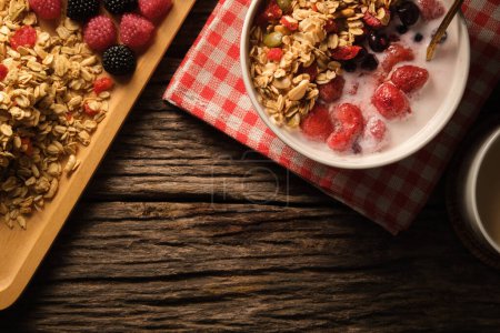 Photo for Crunchy oat granola with fresh milk and berries in bowl on wooden background. Healthy breakfast, vegan, dieting and weight loss concept. - Royalty Free Image