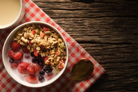 Photo for Healthy breakfast. Crunchy oat granola with fresh milk and berries in a white bowl on wooden background.  Dieting and weight loss concept. - Royalty Free Image