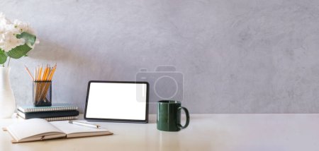 Foto de Tableta digital con pantalla vacía, vasos, portátil y taza de café en mesa blanca. - Imagen libre de derechos