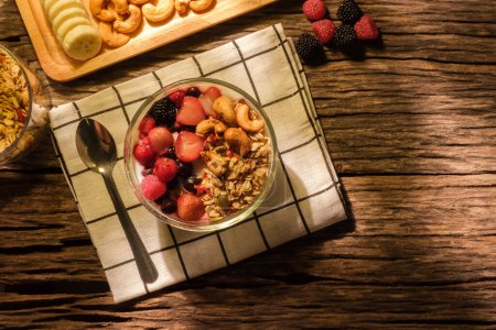 Téléchargez les photos : Yaourt au granola et baies pour un petit déjeuner sain sur table en bois. Vue de dessus avec espace. - en image libre de droit