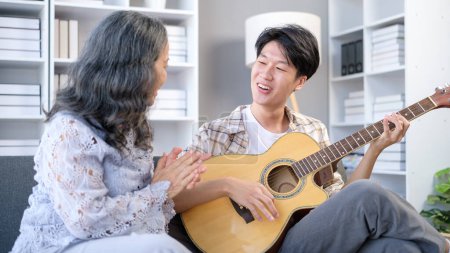 Photo for Overjoyed retired woman and grown up son singing together and playing guitar. Family, generation and recreational activities concept. - Royalty Free Image
