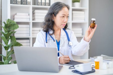 Photo for Female doctor holding bottle with pills, working with medical documents at medical office. Medical care, pharmacy concept. - Royalty Free Image