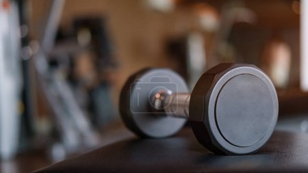 Photo for Close up metal dumbbell on sports bench in sport fitness center. Sports equipment for fitness. - Royalty Free Image