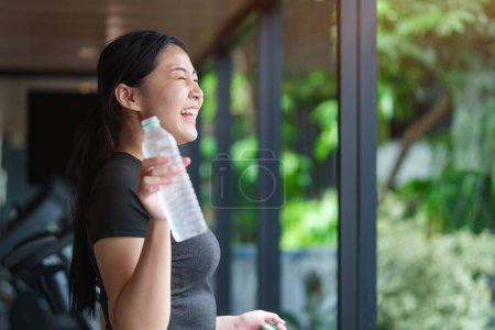 Photo for Thirsty young fitness woman wearing sport clothes drinking fresh water, restin - Royalty Free Image